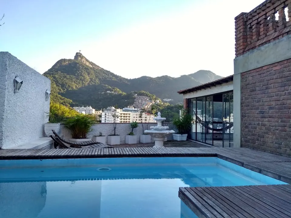 Mirante Laranjeiras rooftop terrace with pool and wooden deck, with Christ the Redeemer on top of Corcovado in the background